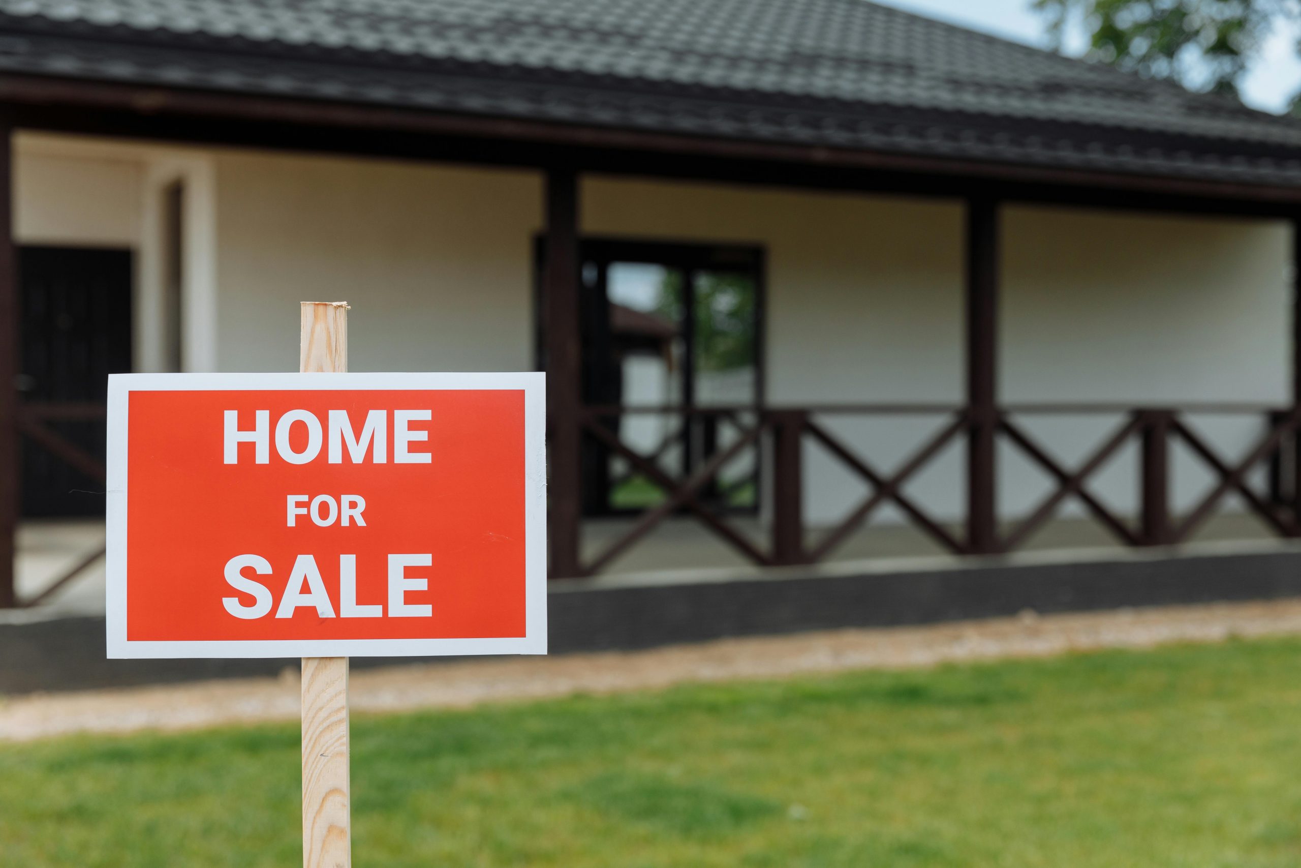home for sale sign with a bungalow house in the background
